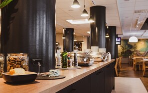 Mostrador de restaurante con diversos alimentos, incluyendo un bol de pan, un plato de queso y un tarro de nueces.