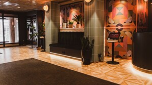 Un hall d’entrée moderne avec des murs aux motifs géométriques, un comptoir d’accueil et des plantes en pot.
