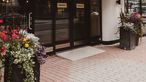 La façade de l’hôtel Vaaruna, avec ses portes d’entrée, une enseigne au-dessus des portes et des jardinières remplies de fleurs sur le trottoir.