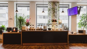 Un espace d’accueil avec un comptoir en bois, des plantes en pot et un téléviseur à écran plat.