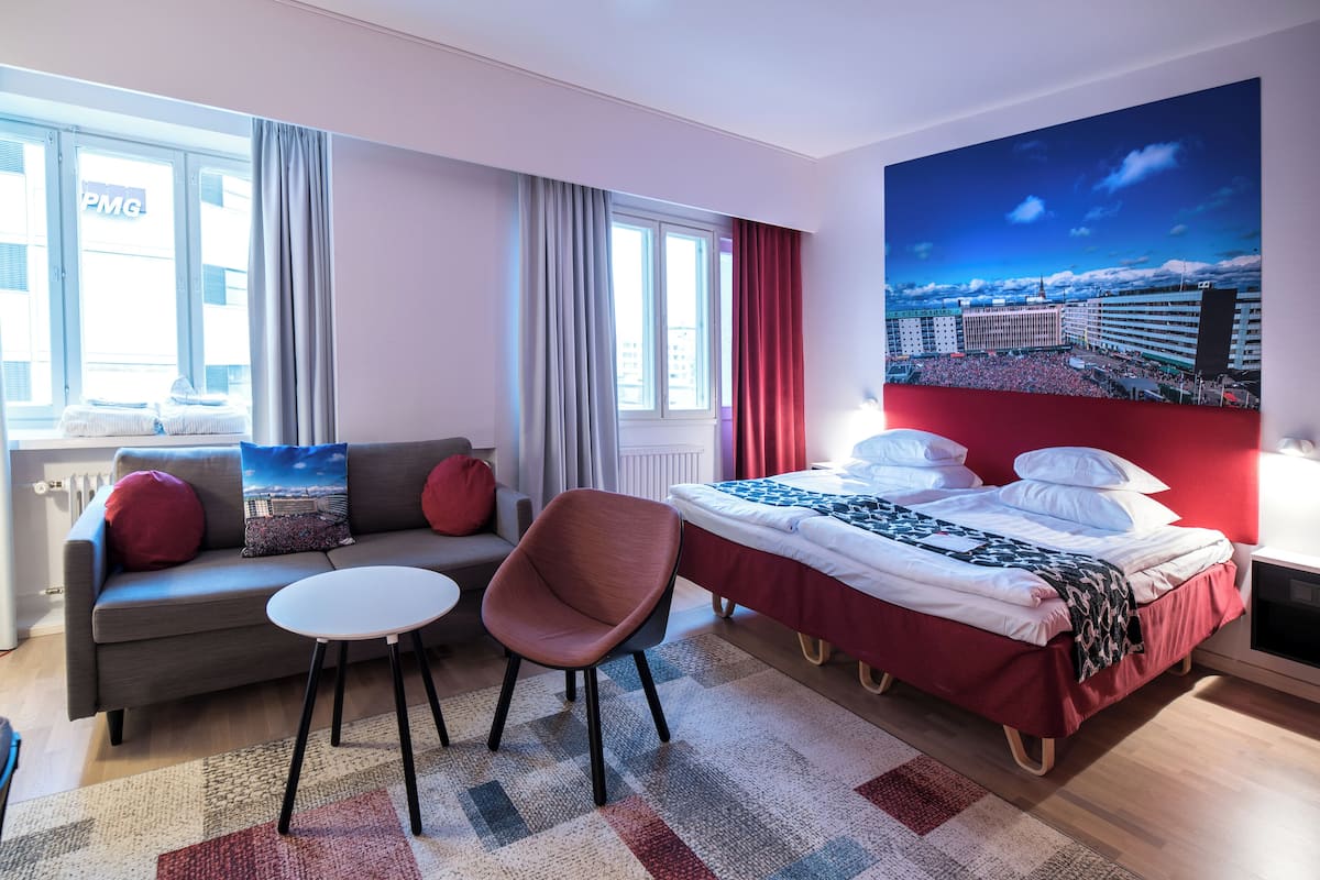 Une chambre d’hôtel moderne équipée d’un lit, d’un canapé, d’une chaise et d’une petite table.