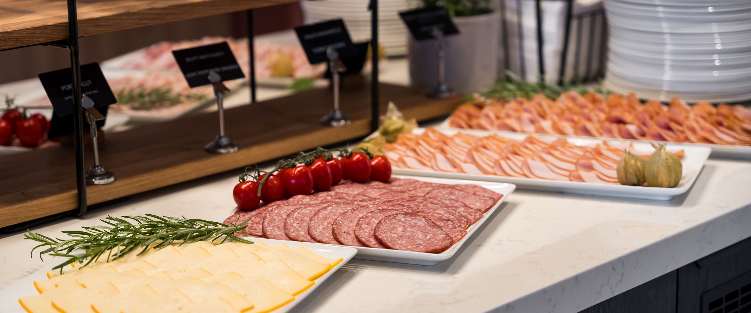Ein Buffet mit verschiedenen Speisen, darunter Aufschnitt, Käse und Gemüse.