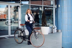 A person standing next to a bicycle with a basket in front of a building with glass doors and a sign that reads "HEIM". - Original Sokos Hotel Vaakuna Mikkeli (Mikkeli)