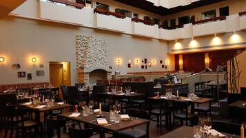 A multi-level dining area with tables set for meals, a fireplace, and a staircase leading to an upper level.