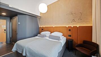 A modern hotel room with a large bed, a small side table, a chair, and a wall with a simple line drawing.