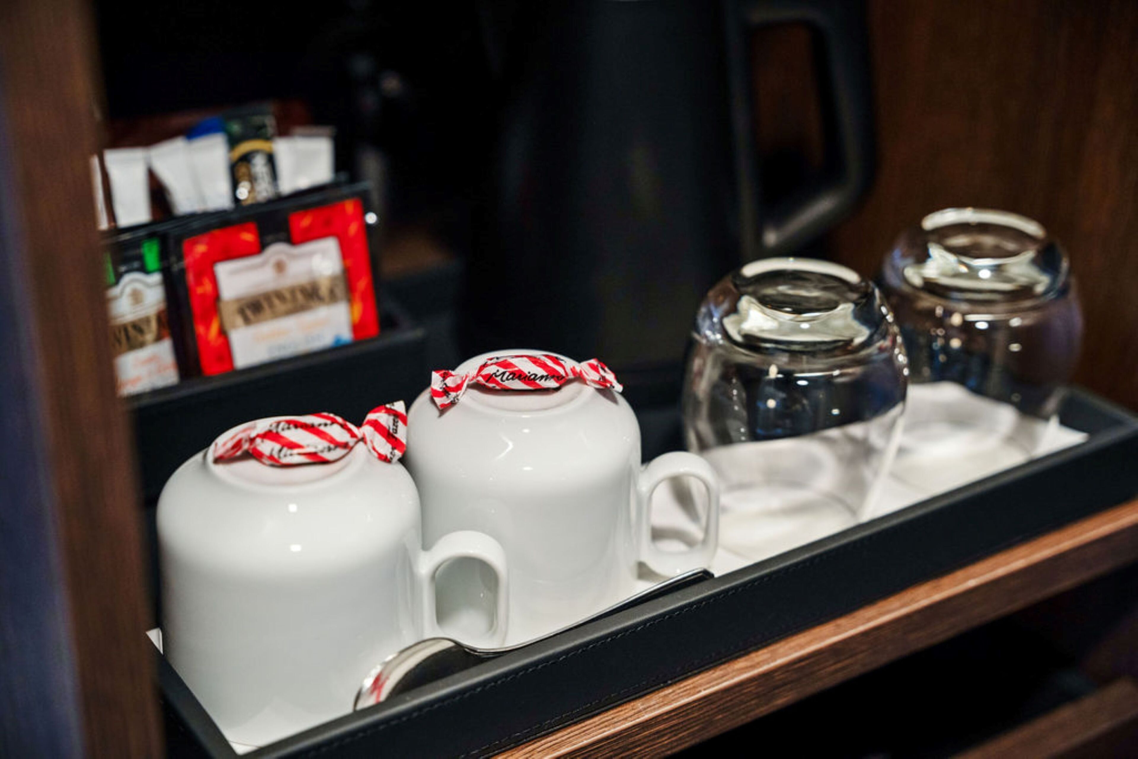 A tray with white teapots and cups, a glass jar, and a black coffee maker.