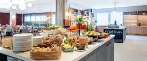 A buffet setup with various food items, plates, and serving utensils. - Original Sokos Hotel Vaakuna Mikkeli (Mikkeli)