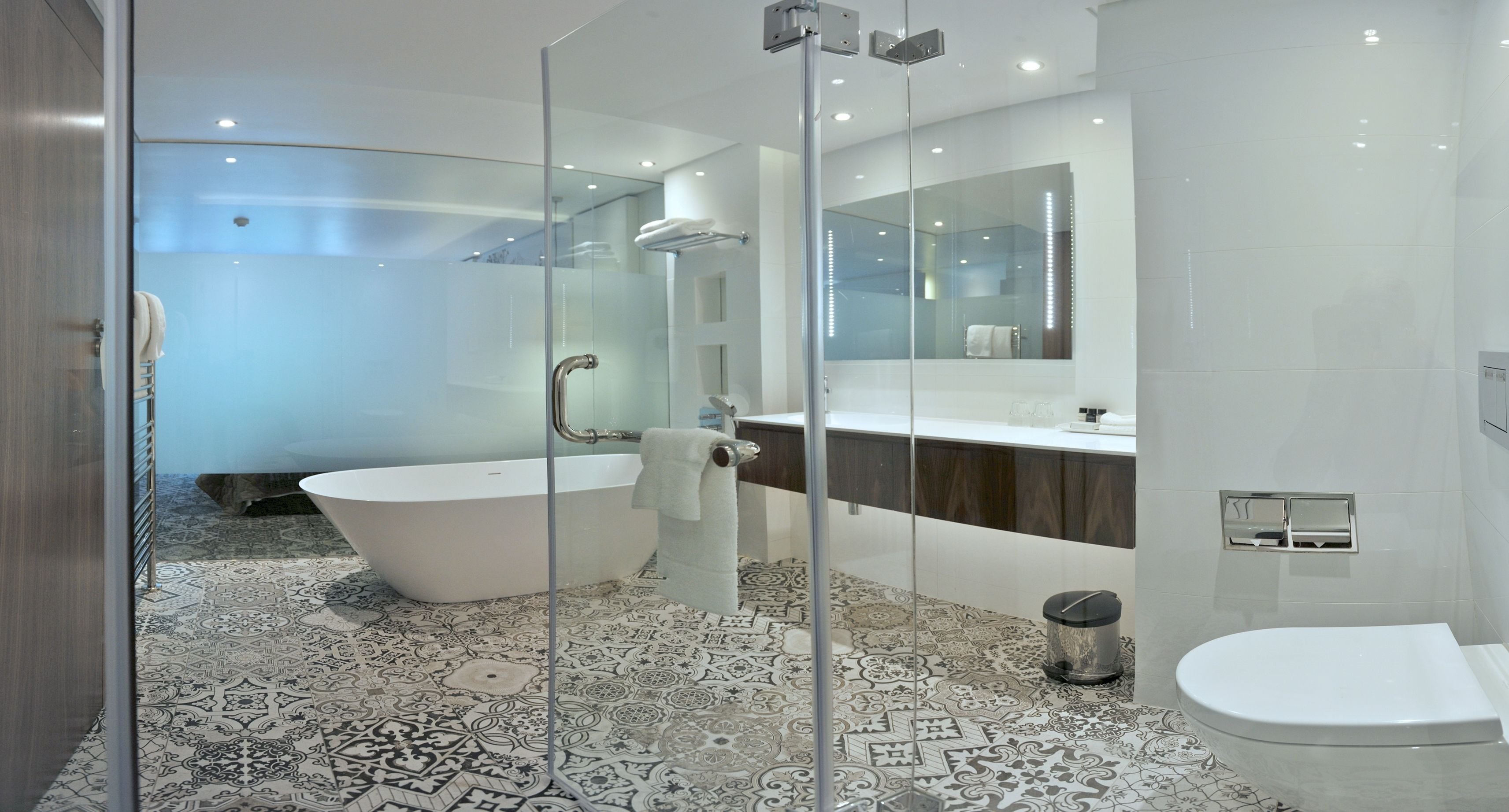 A modern bathroom with a glass-enclosed shower, a freestanding bathtub, and a separate toilet area.