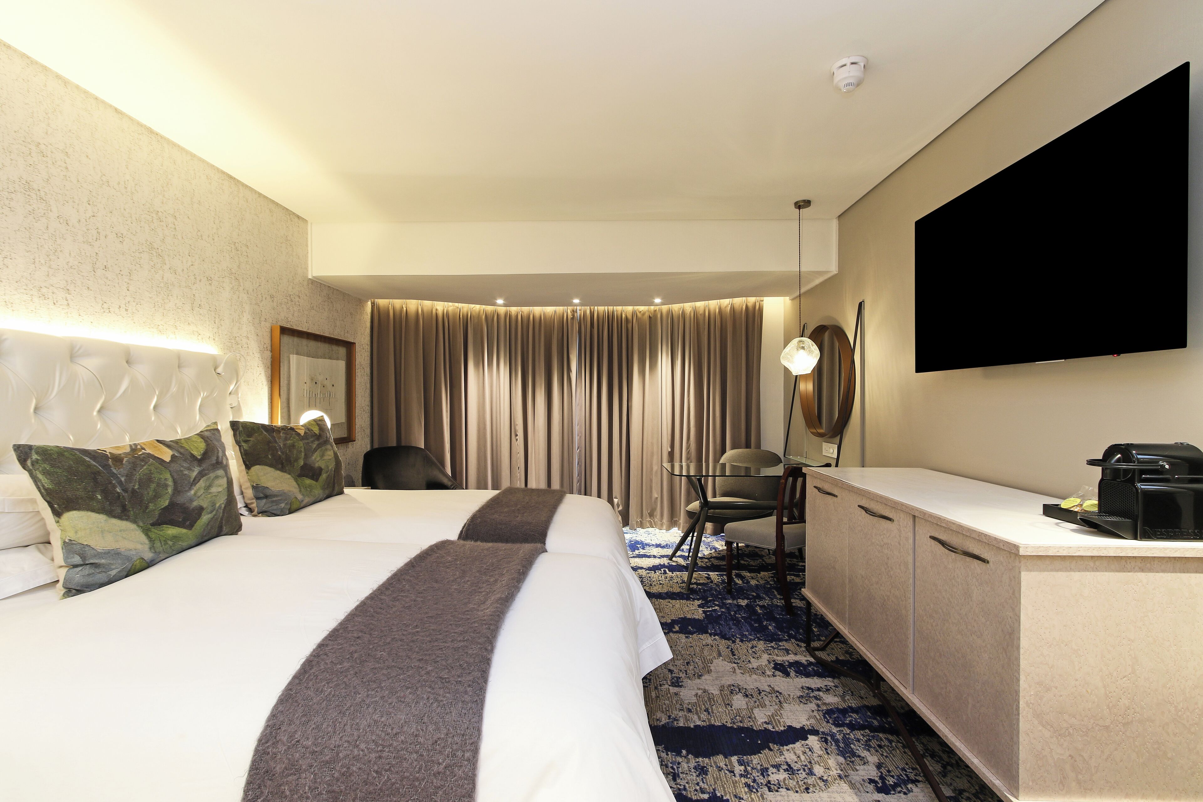 Une chambre d’hôtel dotée d’un grand lit, d’un bureau avec un téléviseur à écran plat, d’une chaise et d’un mini-bar.