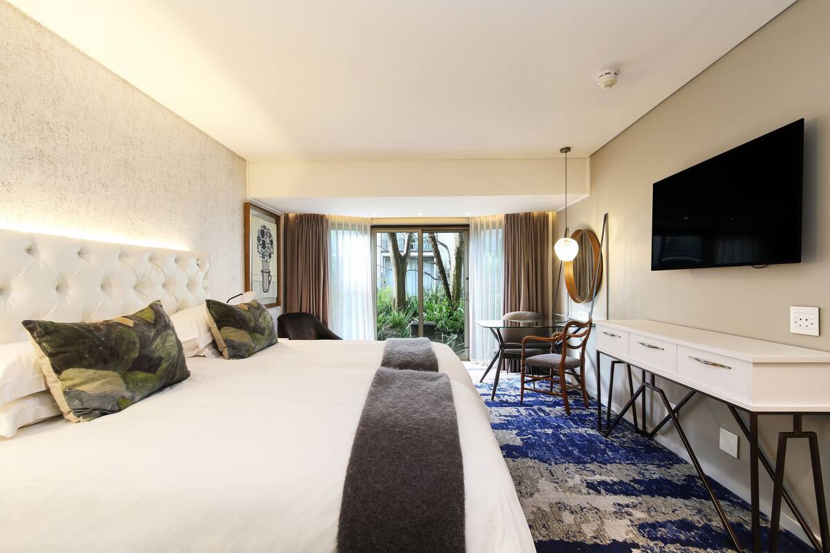 A hotel room with a large bed, a desk, and a TV.