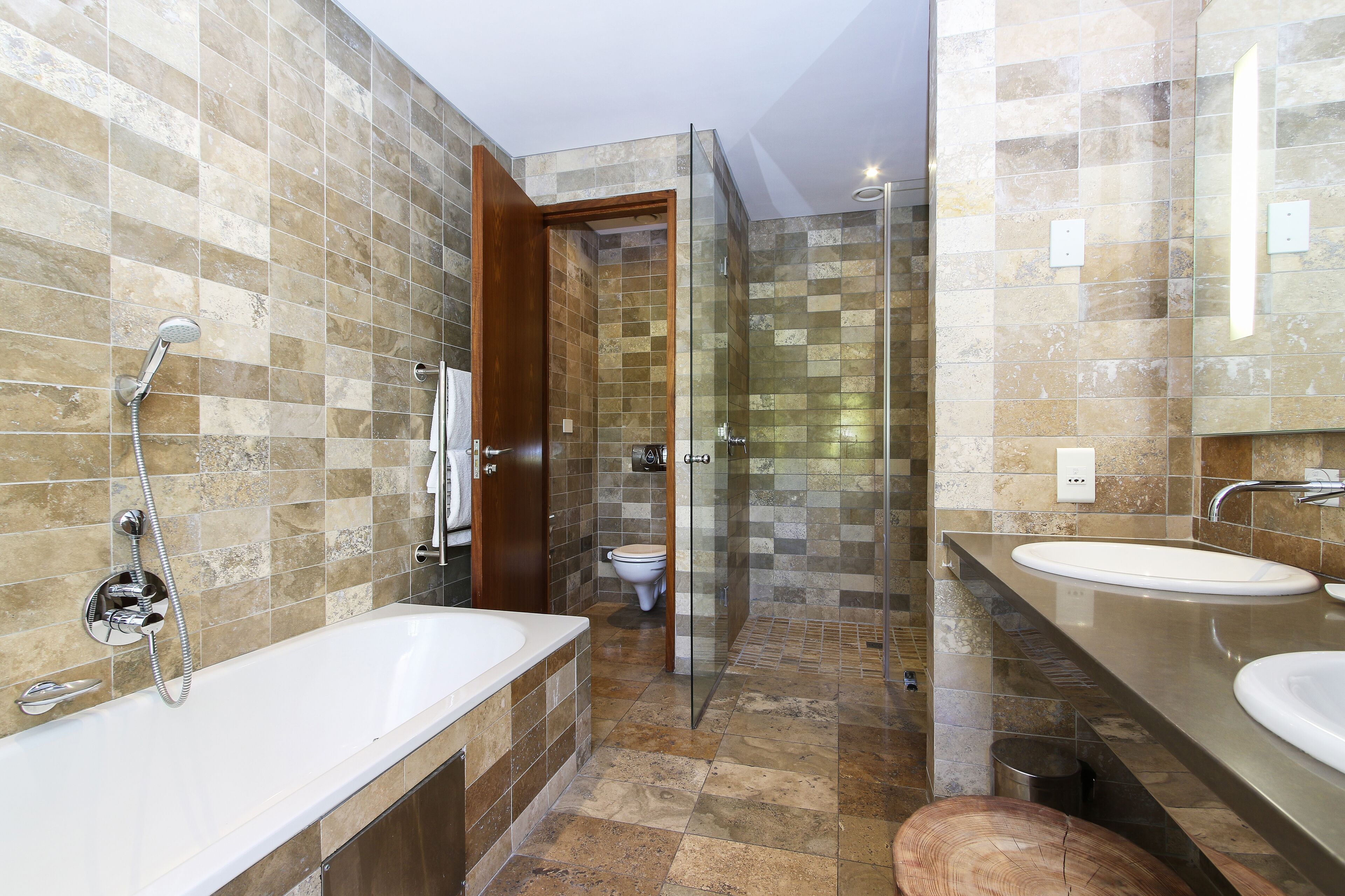 Ein modernes Badezimmer mit Duschkabine aus Glas, einer Badewanne und zwei Waschbecken.