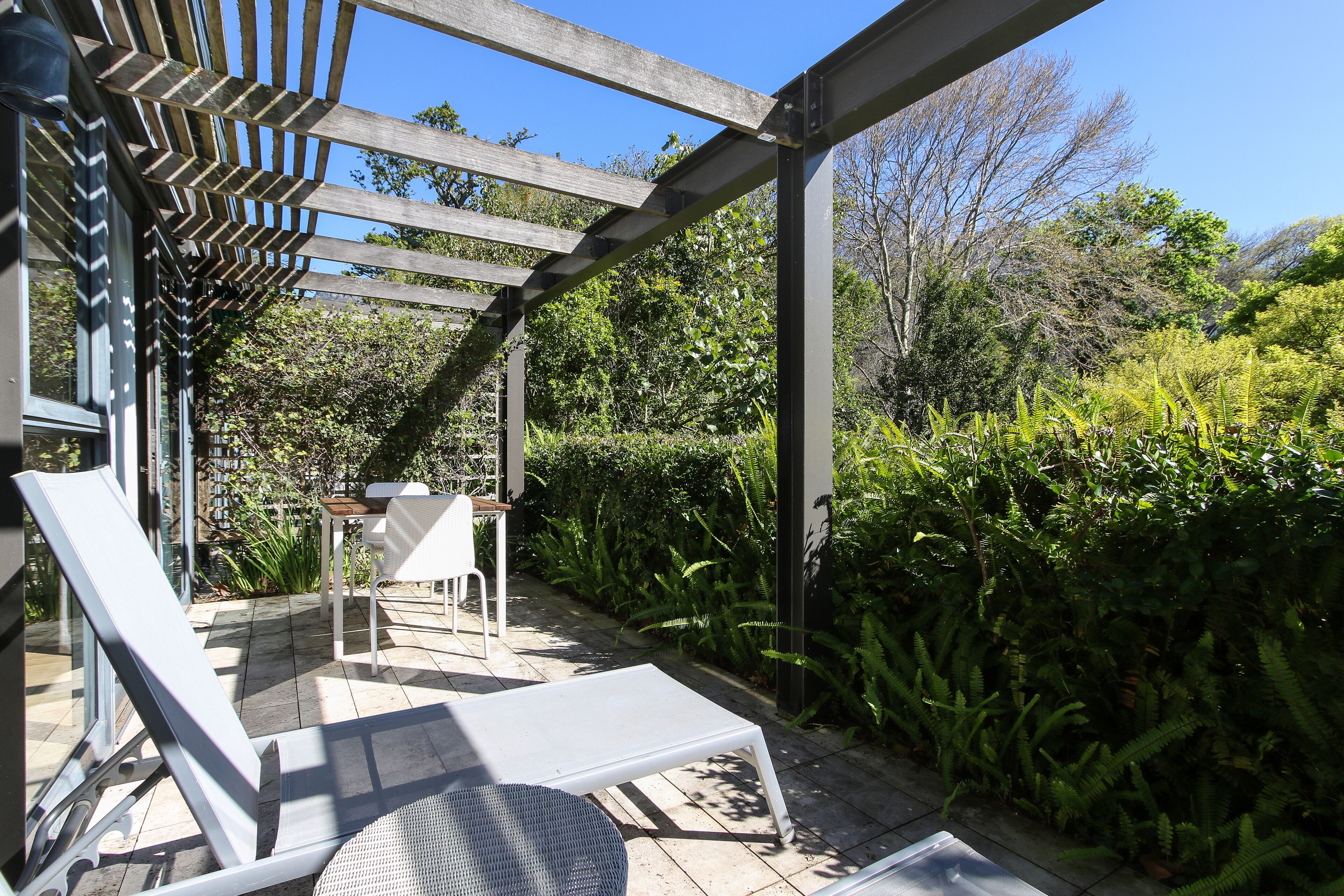 A covered outdoor seating area with a pergola, a table, and chairs.