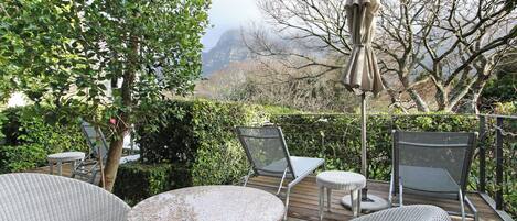 An outdoor patio with wicker furniture, a round table, and a large umbrella.