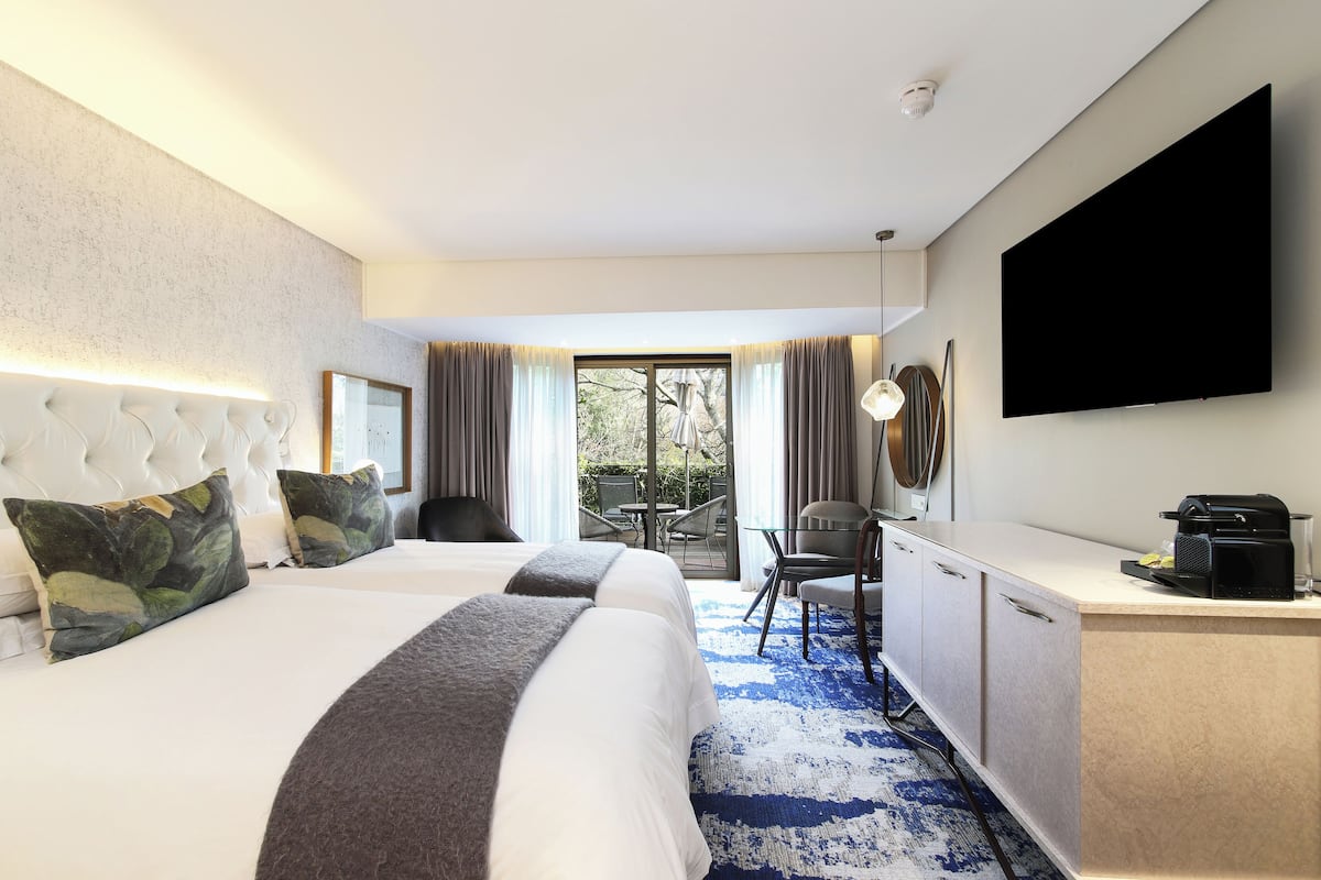 A hotel room with a large bed, a desk, a flat-screen TV, and a view of the outdoors.