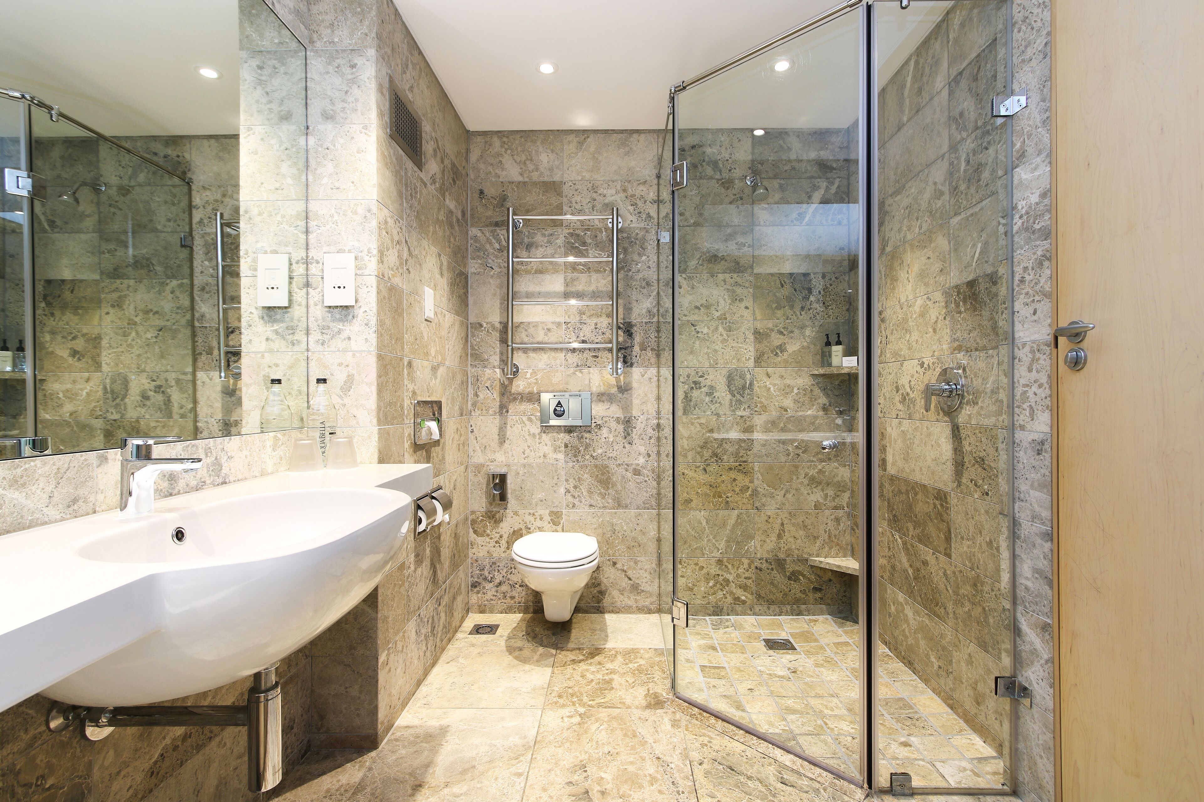 A modern bathroom with a large sink, toilet, and glass-enclosed shower.
