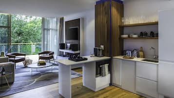 Una cocina moderna con horno integrado, cafetera y zona de comedor con sofá y mesa.