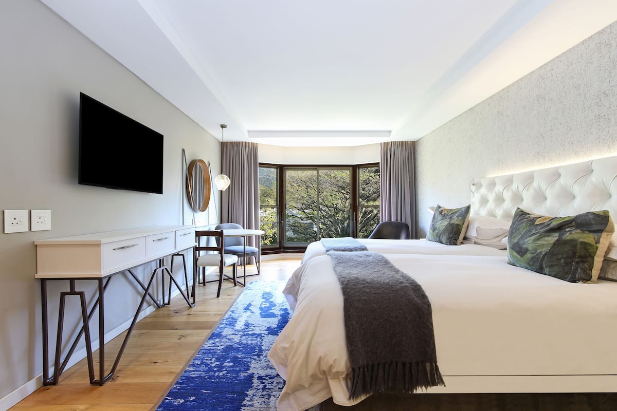 A modern bedroom with a large bed, a desk, and a TV.