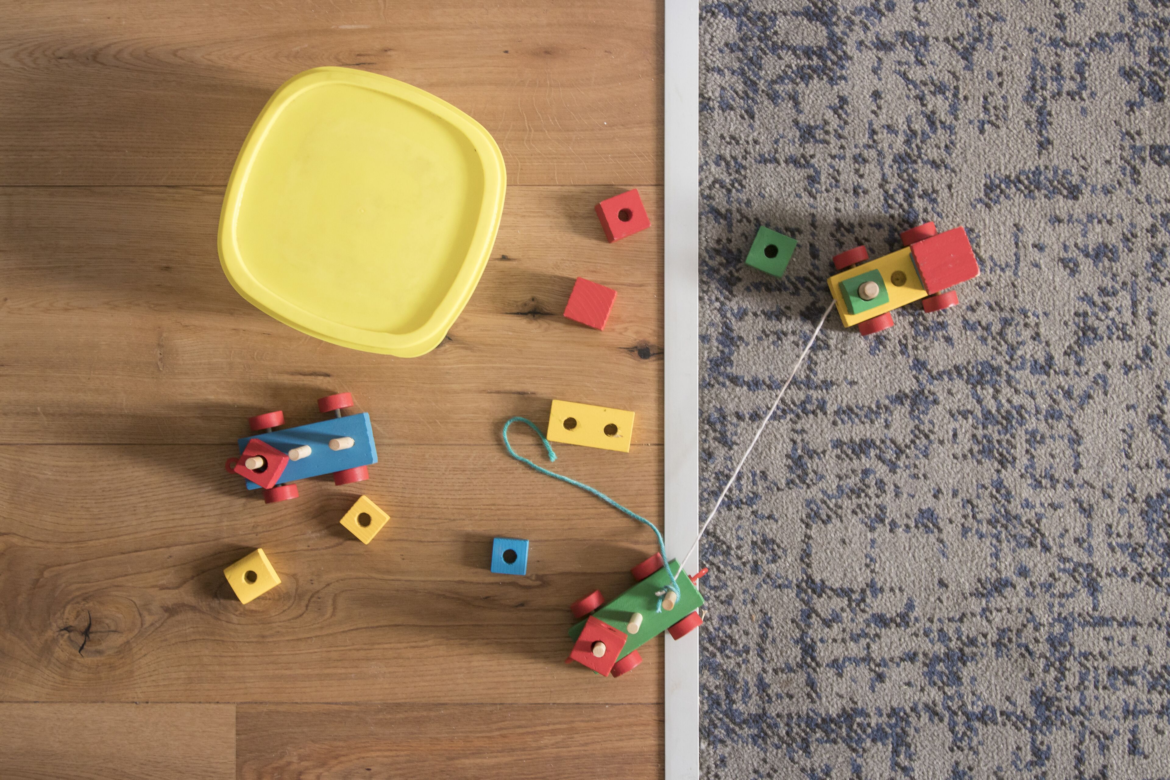 A wooden floor with scattered toys and a yellow tray.