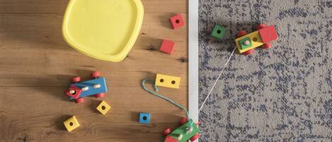 A wooden floor with scattered toys and a yellow tray.