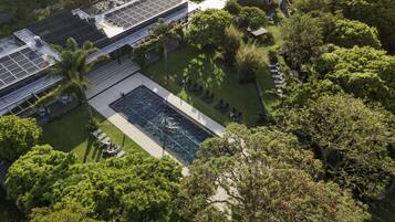 Vista aérea de un hotel con piscina, paneles solares y abundante vegetación.