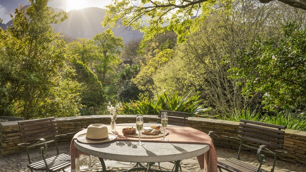 Un área de comedor al aire libre con una mesa redonda, sillas y un banco.
