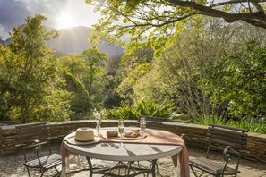 An outdoor dining area with a round table, chairs, and a bench. - Vineyard Hotel (Cape Town)