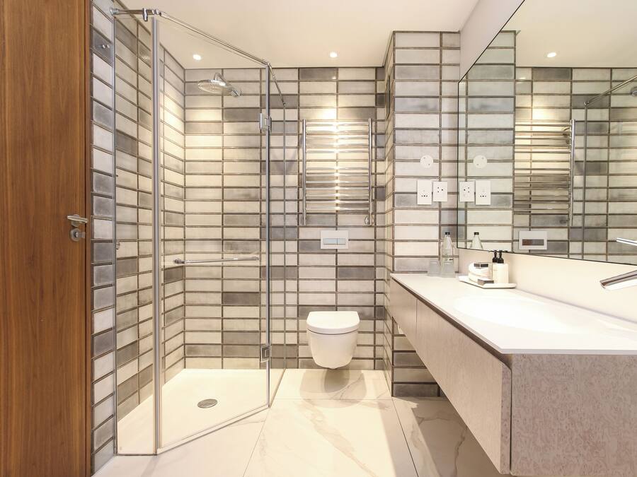 Un baño moderno con cabina de ducha de vidrio, inodoro y tocador con espejo.