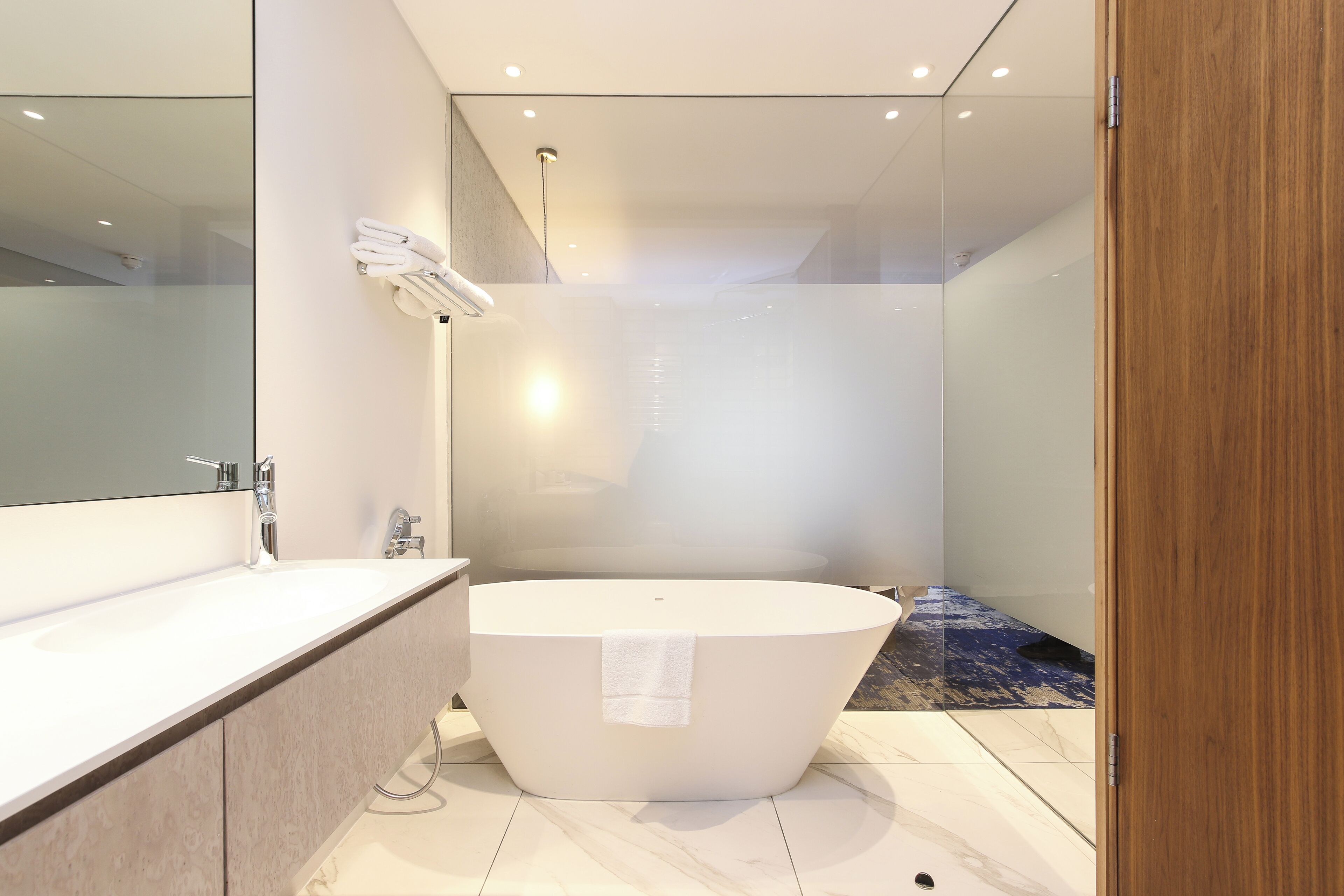 A modern bathroom with a freestanding bathtub, a large mirror, and a glass shower enclosure.