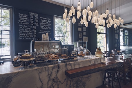 A café with a marble counter displaying pastries and a chalkboard menu.