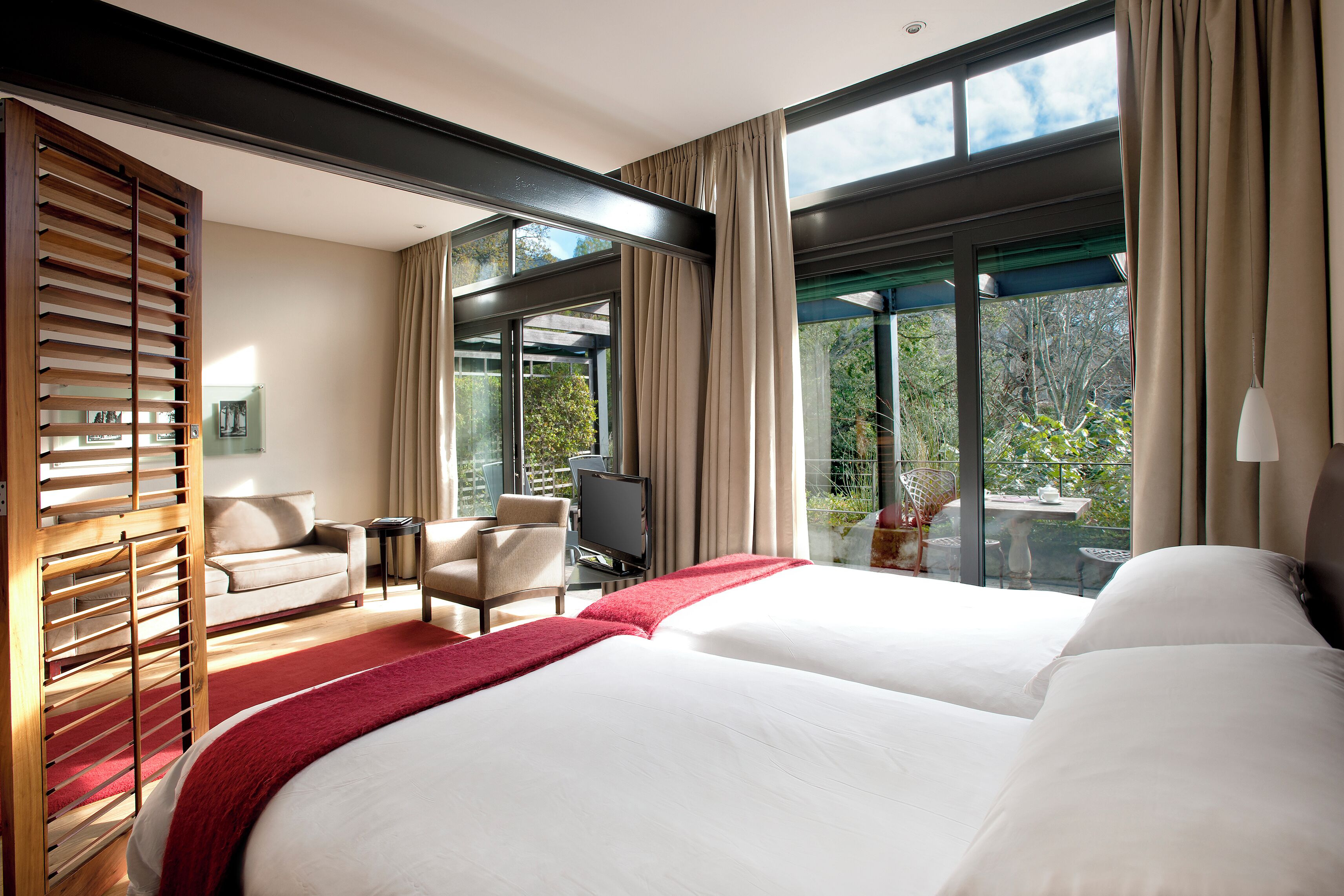 Une chambre d’hôtel avec un grand lit, un canapé, une télévision et un balcon équipé d’une table et de chaises.