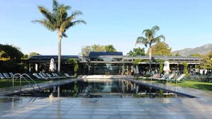 Un área de piscina moderna con sillones de descanso y palmeras.