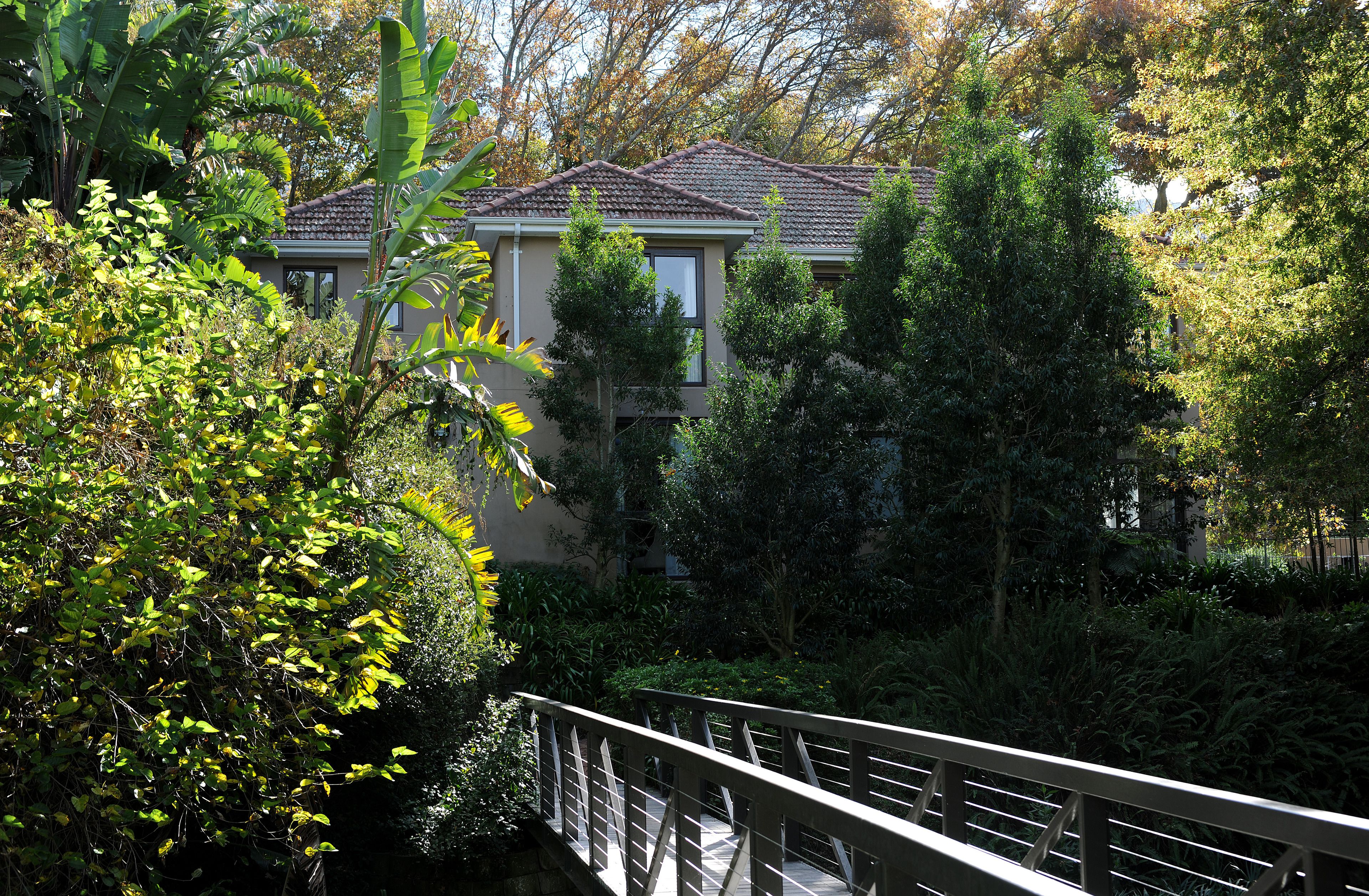 A residential building surrounded by dense foliage and a bridge.