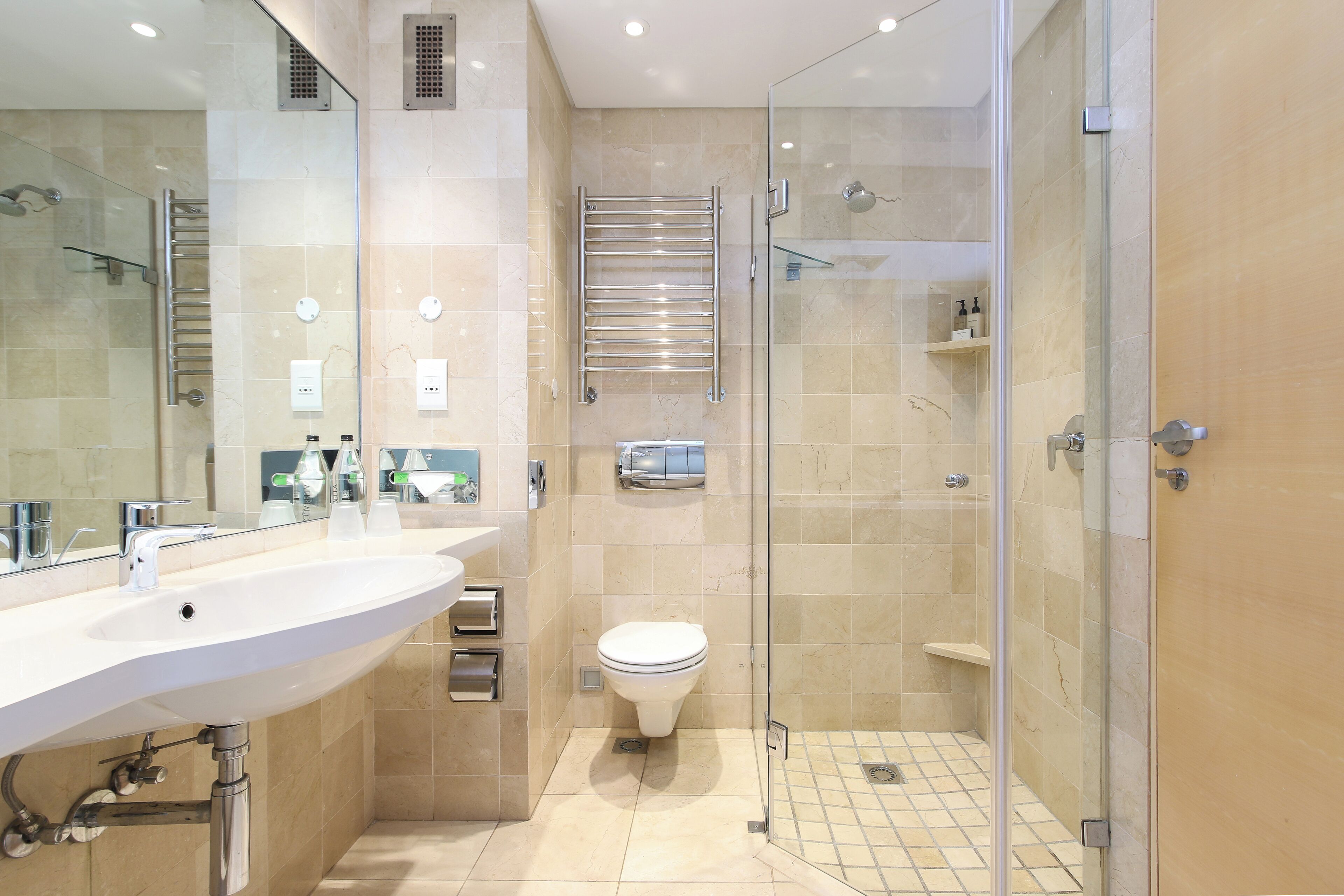 A modern bathroom with a glass shower enclosure, a white sink, and a toilet.