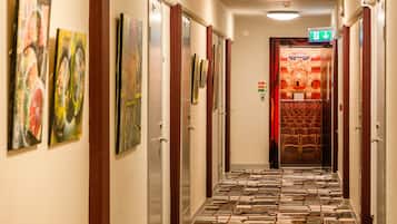 A hotel hallway with artwork on the walls, a patterned floor, and a seating area at the end.
