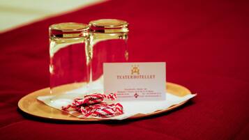 A tray with two salt and pepper shakers and a hotel card on a red fabric surface.