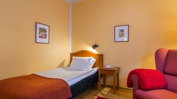 Une chambre d’hôtel avec un lit, une table de chevet, une chaise et deux tableaux encadrés au mur.