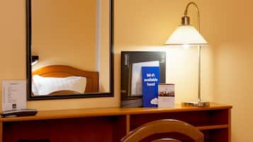 Habitación de hotel con cama, escritorio con lámpara, televisor, teléfono y señalización que indica disponibilidad de Wi-Fi.
