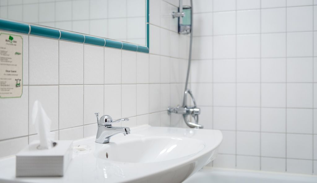 A bathroom with a white sink, a mirror, and a shower.