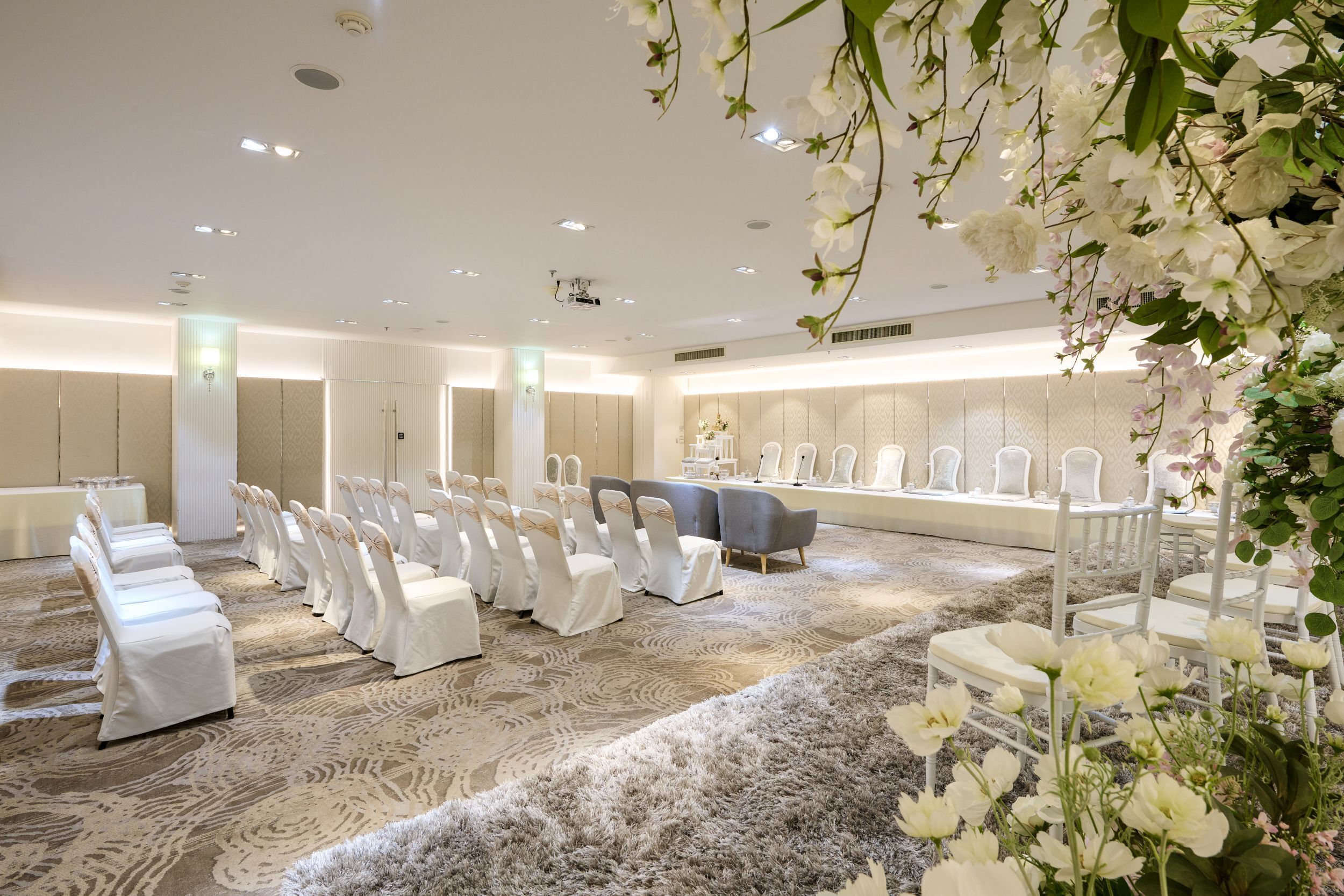 A spacious room with rows of white chairs and a stage area, likely for events or ceremonies.