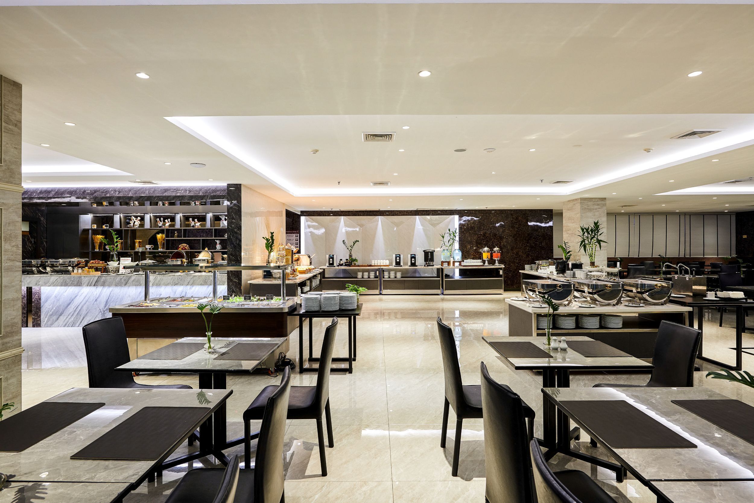 A modern restaurant with a marble counter, black chairs, and a central seating area with a white tablecloth.