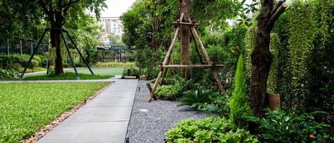 Un sendero serpentea por un parque con árboles y un columpio.