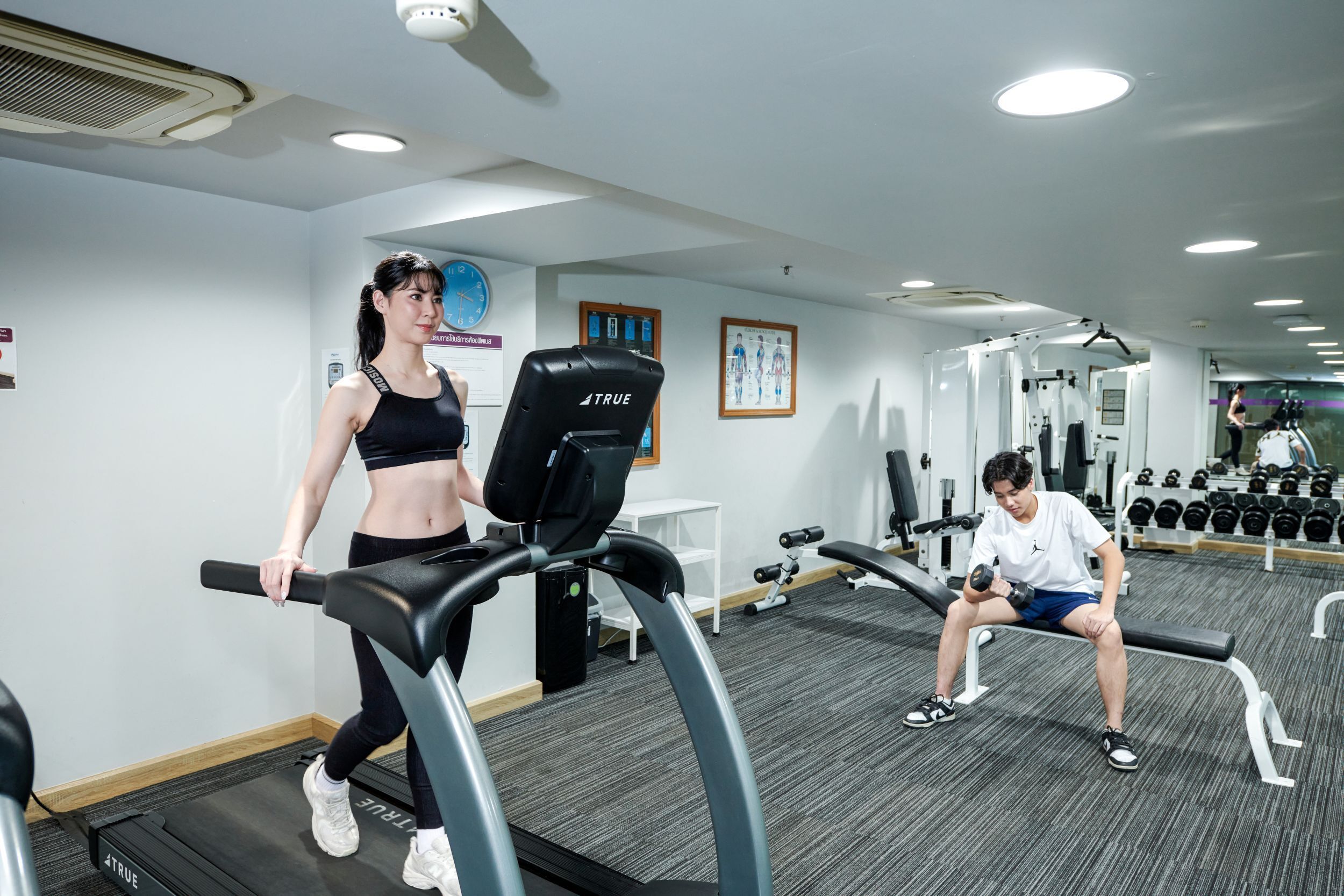 Ett gym med löpband, styrketräningsmaskiner och hantlar.