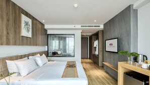 Et moderne hotelværelse med en stor seng, et træskrivebord, et spejl og et fjernsyn.