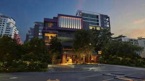 Et moderne hotel med iøjnefaldende indgang, anlagt have og parkeringsområde.