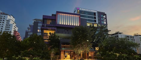 A modern hotel with a prominent entrance, a landscaped garden, and a parking area.