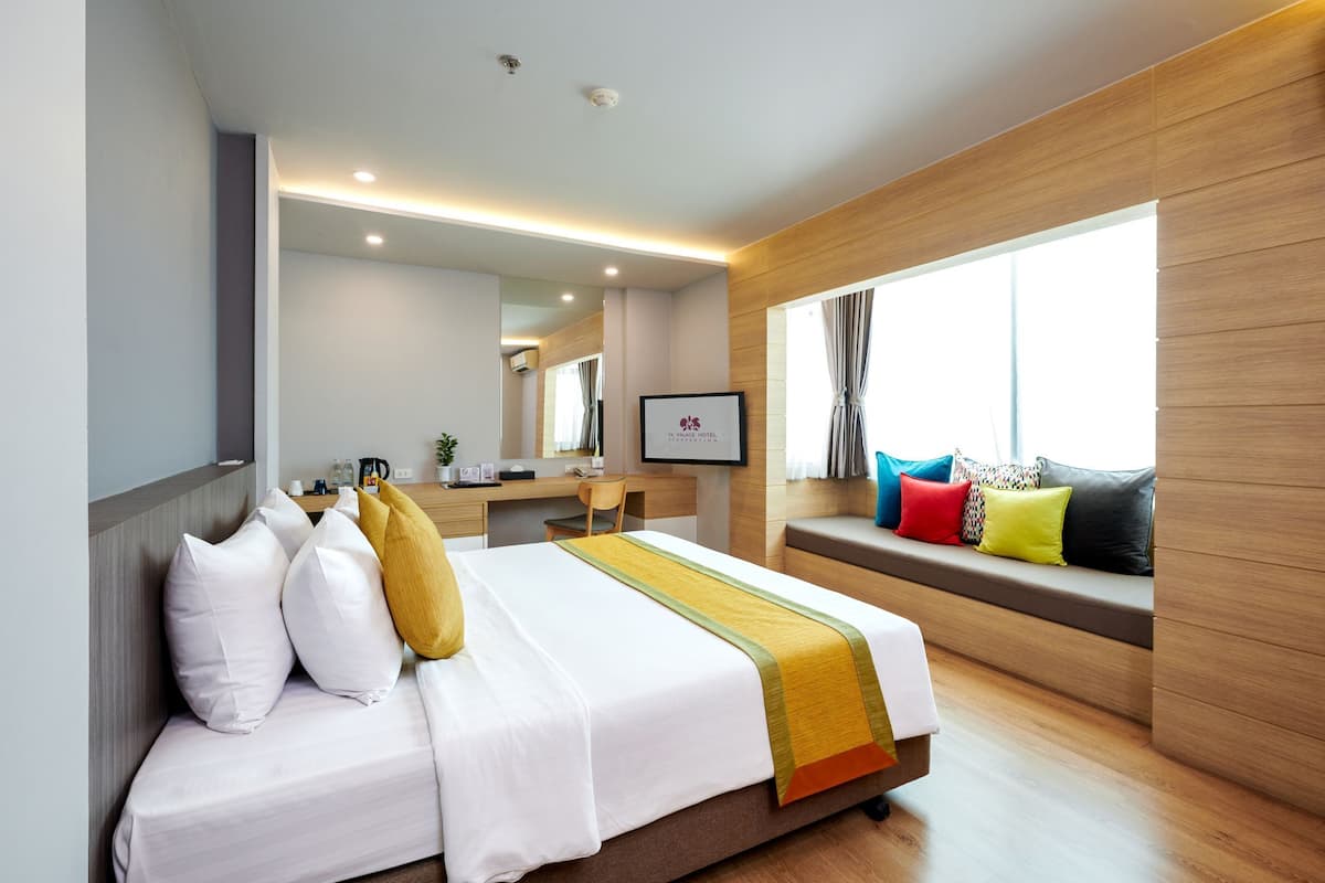 A modern hotel room with a neatly made bed, a desk, and a window with a view.