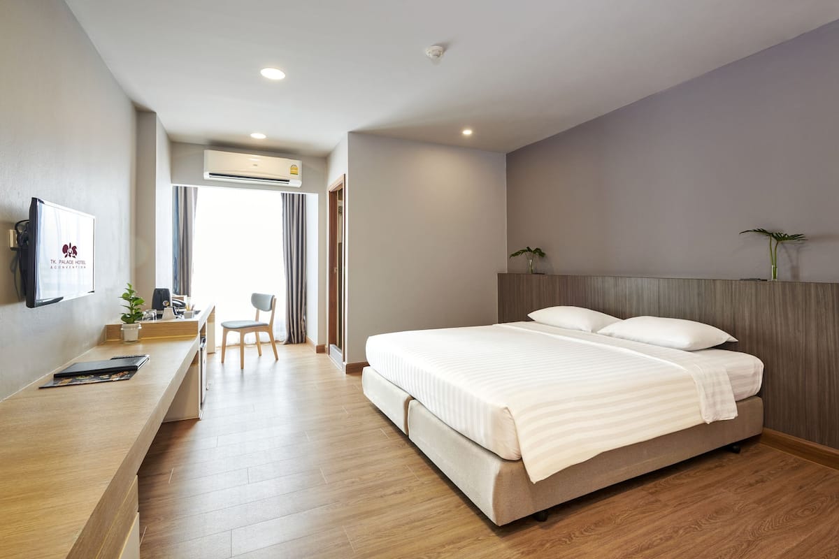 A modern hotel room with a large bed, a desk with a chair, and a TV on the wall.