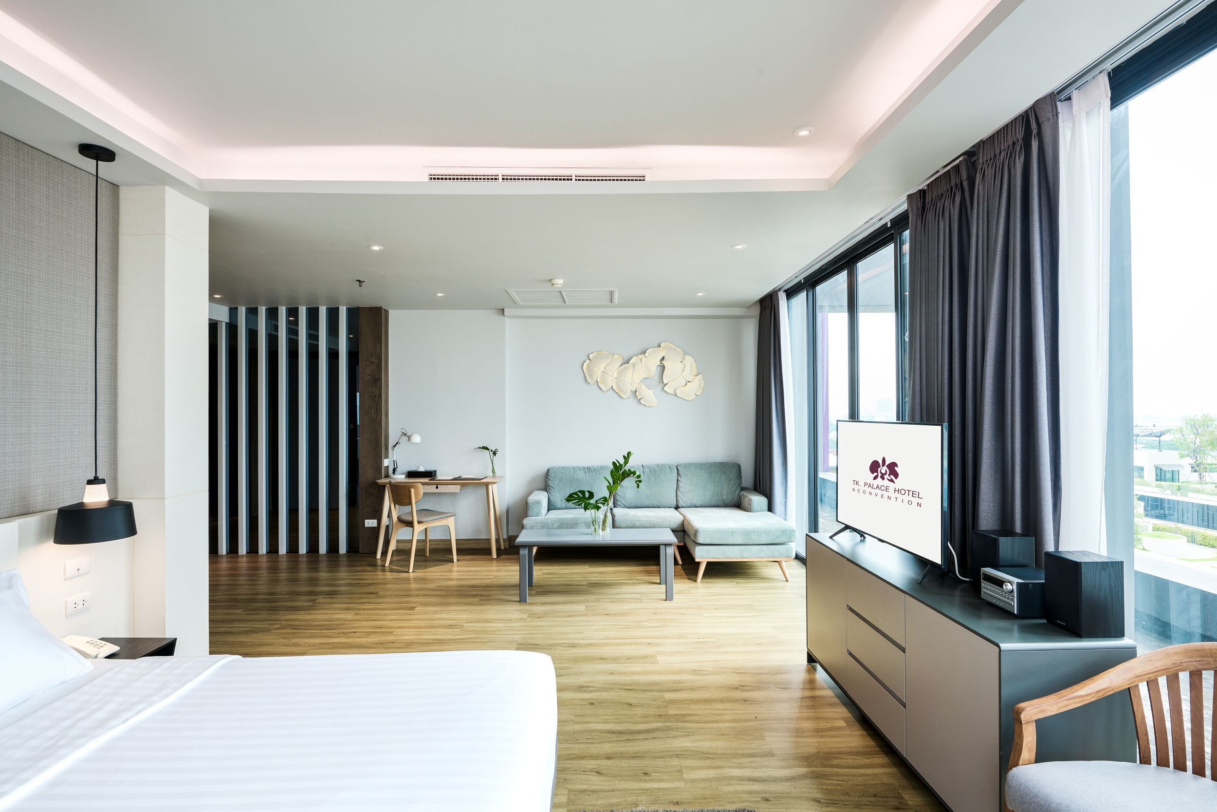 Quarto de hotel moderno com uma cama grande, uma escrivaninha, um sofá e uma televisão.