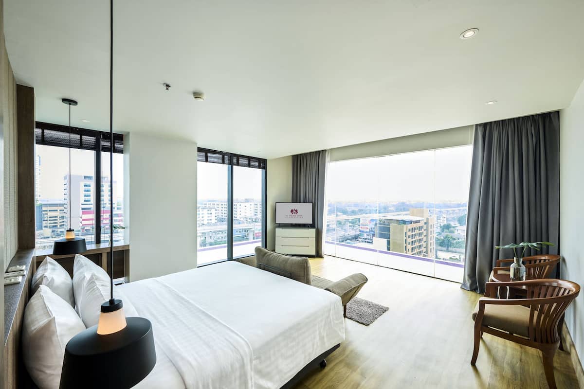 A modern hotel room with a large bed, a desk, and a view of the city.