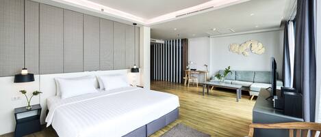 A modern hotel room with a large bed, a desk, a sofa, and a TV.